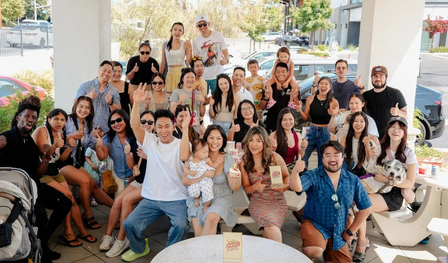 Friends of all ages, kids and dogs included, cheering at a Friends Club gathering
