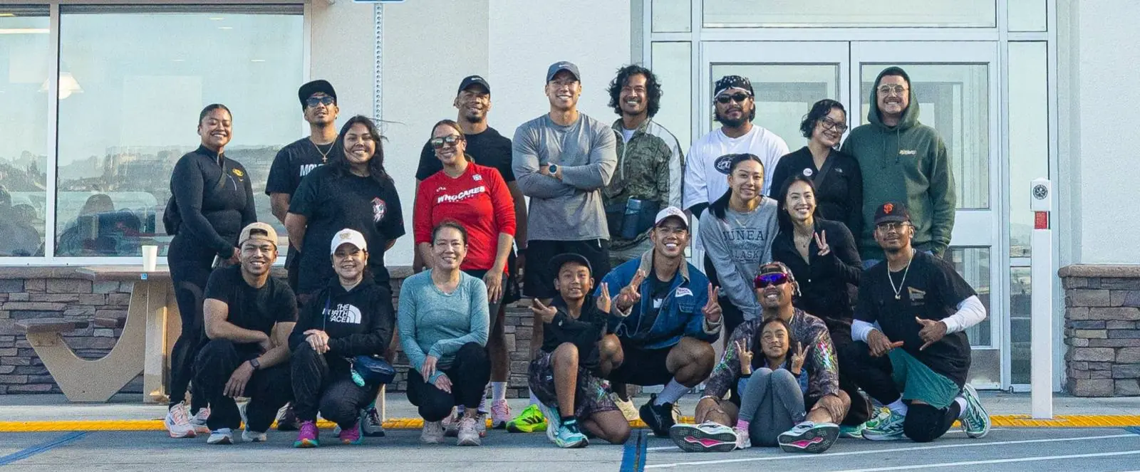 Friends Run Club members posing together after a morning run, some kneeling and flashing peace signs