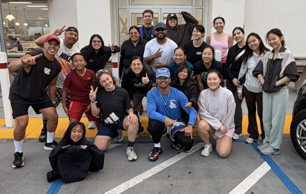 Friends Run Club members gathered together after an evening run, flashing peace signs